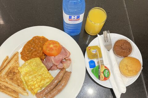 Ala catte breakfast with orange juice, water and vanilla and bran muffins with utensils