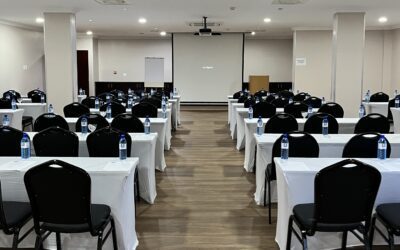 Conference room with black cushioned chairs, table with white covers and white board with projector