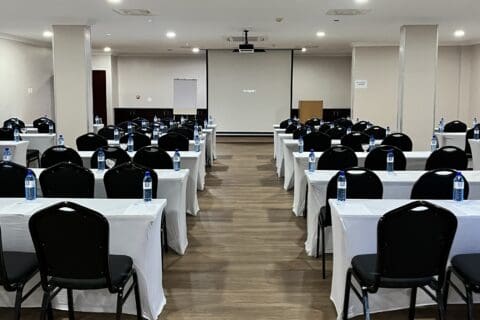Conference room with black cushioned chairs, table with white covers and white board with projector