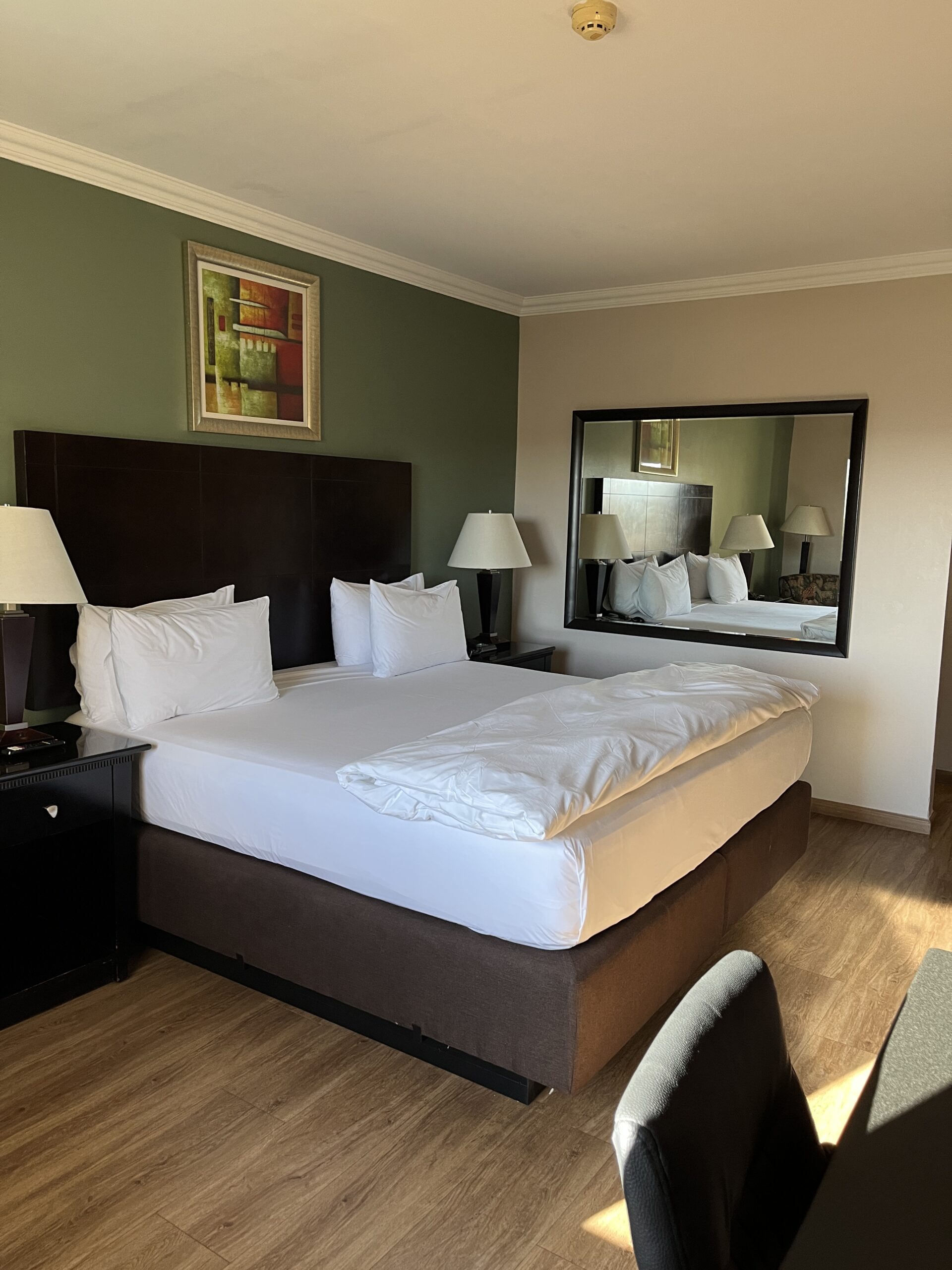 King bed with white linen sheets and covers with 2 lights and pedestals